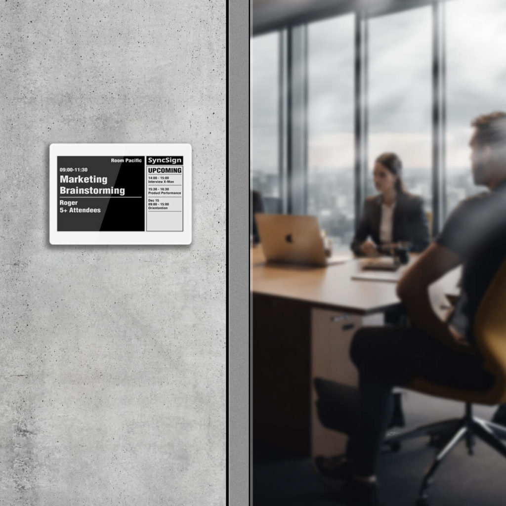 Display e-ink Sync-Sign installato su una porta di una sala riunioni moderna